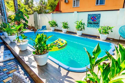 a pool with a surfboard in the middle of plants at Villa Shell in Zatoka