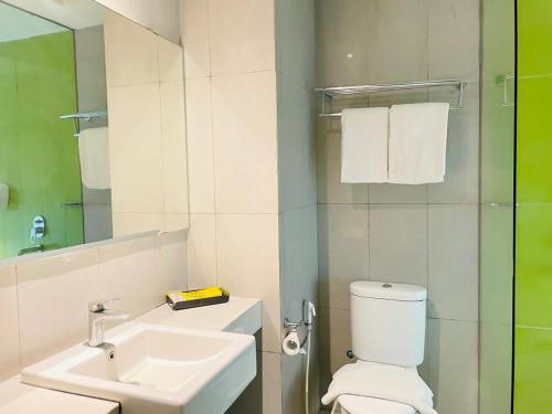 a bathroom with a sink and a toilet and a mirror at KHAS Surabaya in Surabaya
