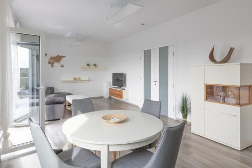 ein weißes Esszimmer mit einem weißen Tisch und Stühlen in der Unterkunft Moderne 2 Zimmer Ferienwohnung mit Dachterrasse - 95qm in Bremerhaven