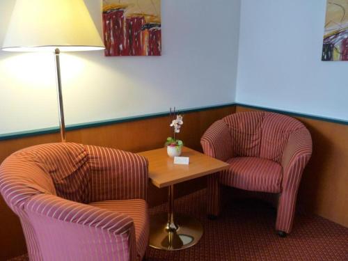 a room with two chairs and a table and a lamp at Parkhotel zur Klause in Bad Hall
