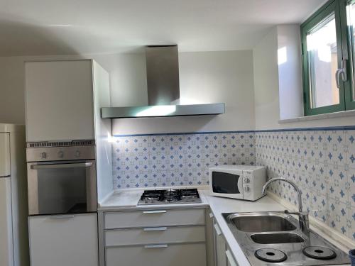 eine Küche mit einer Spüle und einer Mikrowelle in der Unterkunft Splendida taverna dotata di tutti i comfort a 500 mt dal mare in Marina di Carrara