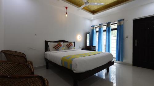 a bedroom with a bed and a window with blue curtains at Vibgyor Villa in Munnar
