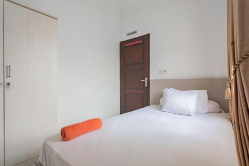 een slaapkamer met een wit bed met een oranje voorwerp erop bij Small Homestay Syariah Sikembar Ciwidey Mitra RedDoorz in Bandung