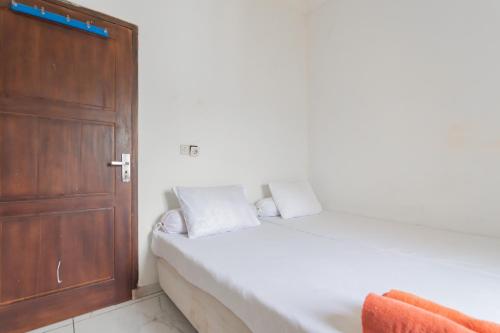 a bedroom with a white bed and a wooden door at Small Homestay Syariah Sikembar Ciwidey Mitra RedDoorz in Bandung