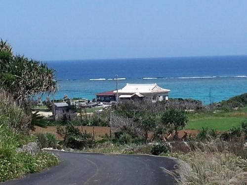 a house on the side of a road near the ocean at Minshuku Myojoso in Yoron