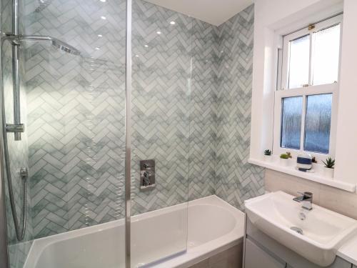 a bathroom with a shower and a tub and a sink at 3 Top View Cottages in Salcombe
