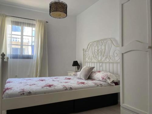 a white bedroom with a bed with a white headboard and a window at MiRA MAR in Lajita