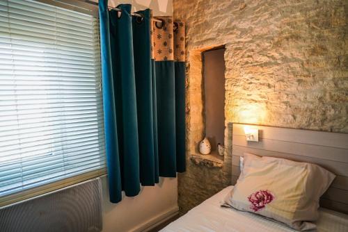 - une chambre avec un lit doté de rideaux bleus et d'une fenêtre dans l'établissement Studio du sentier des ocres, à Roussillon