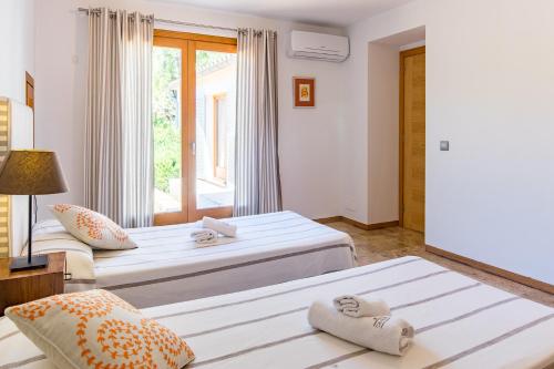 a bedroom with two beds and a window at Villa Cal Padri By SunVillas Mallorca in Pollença