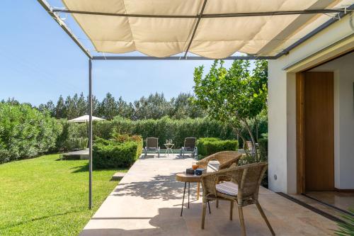 a patio with a table and chairs under an umbrella at Villa Cal Padri By SunVillas Mallorca in Pollença