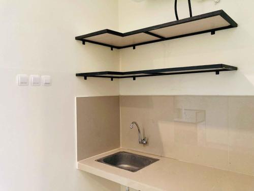 a kitchen with a sink and a shelf on the wall at Hartono Inn Seturan Mitra RedDoorz in Seturan