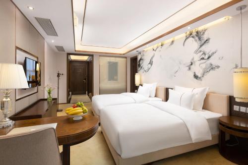 a bedroom with a large white bed and a table at Shenzhen Bay Hisoar Hotel in Shenzhen