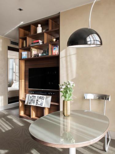 a living room with a table and a television at ME Milan Il Duca in Milan