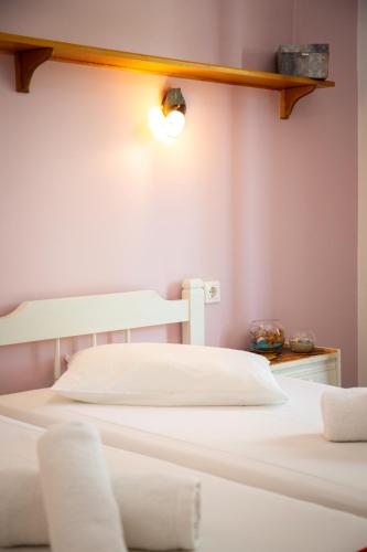 two white beds in a room with a light on the wall at Zervos Apartments Bouka in Lefkímmi