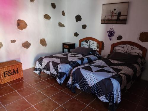 twee bedden in een kamer met rotsen aan de muur bij la casita de Máguez in Máguez