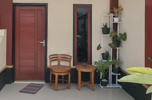 une porte rouge avec deux chaises, une table et quelques plantes dans l'établissement Pondok Sundawa 2 Pangandaran Mitra RedDoorz, à Pangandaran