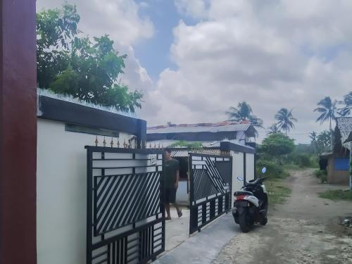 un homme debout à côté d'une porte avec une moto dans l'établissement Pondok Sundawa 2 Pangandaran Mitra RedDoorz, à Pangandaran
