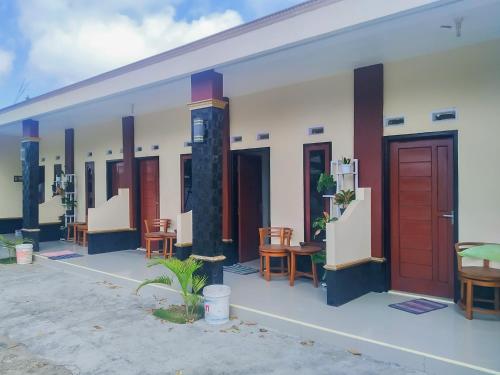 Une rangée de maisons avec des portes rouges et des chaises dans l'établissement Pondok Sundawa 2 Pangandaran Mitra RedDoorz, à Pangandaran