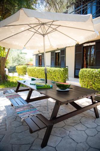a wooden picnic table with an umbrella on a patio at Zervos Apartments Bouka in Lefkímmi