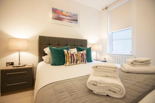 a bedroom with a bed with towels on it at Urban Living's - The King Edward II Luxury Apartment in the heart of Windsor in Windsor