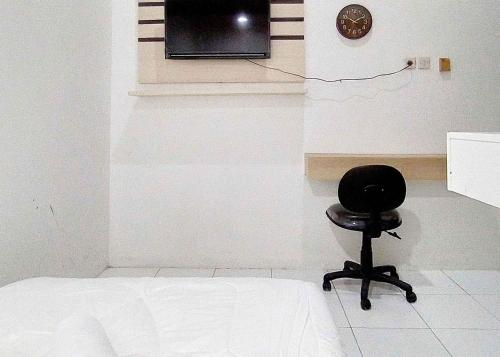 a chair in a room with a tv on a wall at Guest House Kembar Syariah Semarang RedPartner in Jatingaleh