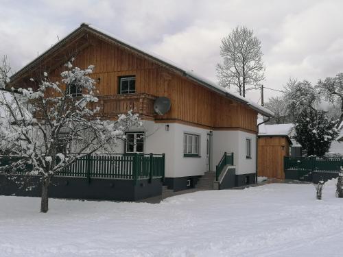 a house with a snow covered yard in front of it at DAS JOHANN Apartments im Ausseerland in Bad Aussee