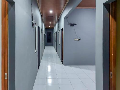 an empty hallway with white tiles on the floor at Guest House Kembar Syariah Semarang RedPartner in Jatingaleh