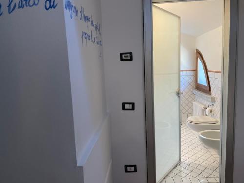 uma casa de banho com um WC e uma porta de duche em vidro. em Splendida camera familiare con lucernario a 500 mt dal mare em Marina di Carrara