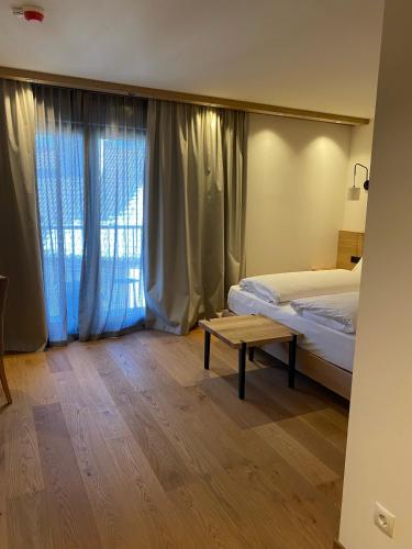 a bedroom with a bed and a table in front of a window at Hotel Mühlenerhof in Campo Tures