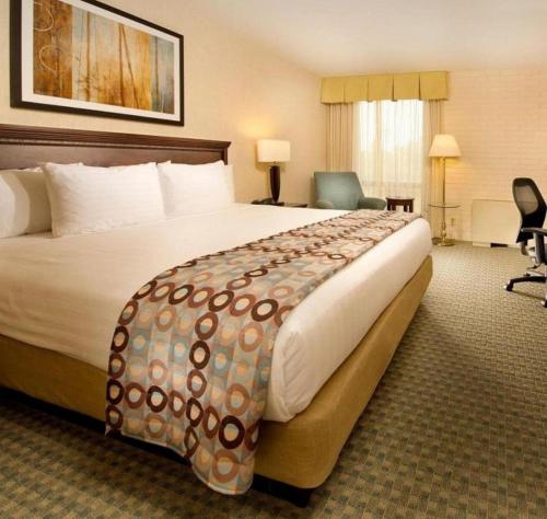 カンザスシティにあるHotel Lotus Kansas City Stadiumの大きなベッドと椅子が備わるホテルルームです。