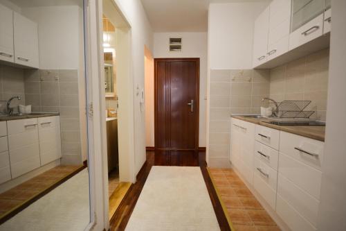 une cuisine avec des placards blancs et une porte marron dans l'établissement Apartman In Lux, à Vrnjačka Banja