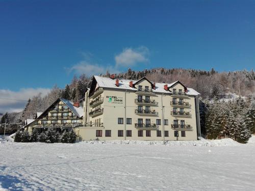 a large building in the snow with snow covered ground at Hotel Zimnik Luksus Natury Spa & Wellness in Szczyrk