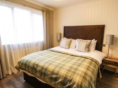 a bedroom with a large bed with a plaid blanket at Island View House in Ballachulish