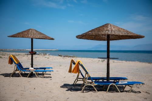 two beach chairs and umbrellas on a beach at Zervos Apartments Bouka in Lefkímmi