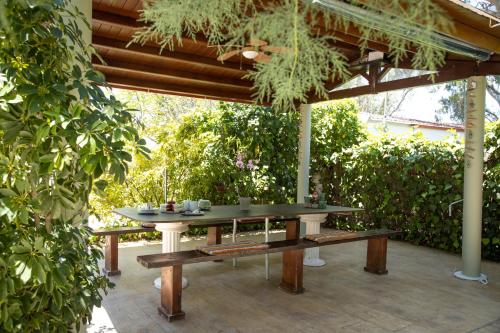 a table and benches under a wooden pergola at Zervos Apartments Bouka in Lefkímmi