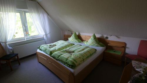 a bedroom with a bed with green sheets and a window at Ferienwohnung-Amanda-2 in Bad Zwischenahn