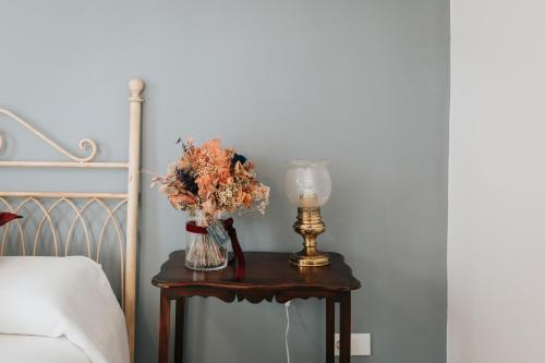 a vase of flowers on a table next to a bed at Casa da Catedral Jerónimo in Badajoz