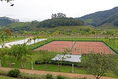 an empty tennis court with trees and mountains in the background at Fazzenda Park Resort in Gaspar