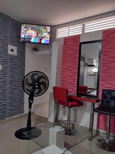 Cette chambre dispose d'un bureau, d'un ventilateur et d'une télévision. dans l'établissement ALELI, NORTE cerca terminal, entr/sal aerpto, orquideorama,c de eventos valle del pcfco, base aérea mfs, à Cali