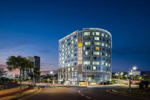 un edificio de cristal alto con un reloj. en Shin Shin Hotel Jeju Worldcup, en Seogwipo