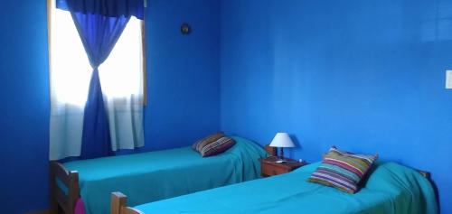 Habitación azul con 2 camas y ventana en Casa Nona Rosa en San Carlos de Bariloche