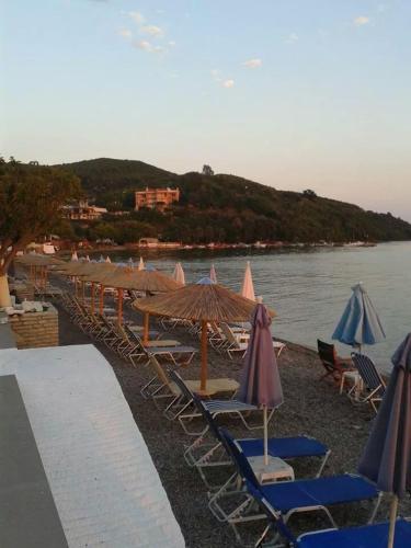 a row of chairs and umbrellas on a beach at Delfini Hotel in Menídion