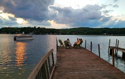 a group of people sitting on a dock with a boat at Birch Knoll Motel in Laconia
