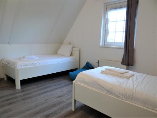 a small room with two beds and a window at Vakantiewoning Zandkreek in Kortgene