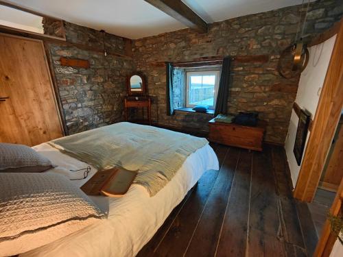 a bedroom with a bed and a stone wall at Le Clos des Brumes in Stoumont
