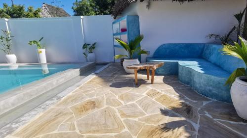 a patio with a blue couch and a table next to a pool at Villa Malaika in Jambiani