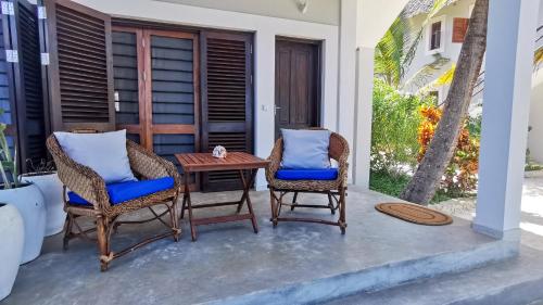 a patio with two chairs and a table at Villa Malaika in Jambiani