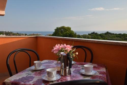 a table with a vase of flowers on a balcony at Anita's Terrace Apartment in Zambratija