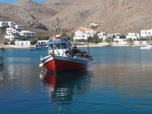 a red and white boat floating in a body of water at Sirokos in Karavostasi