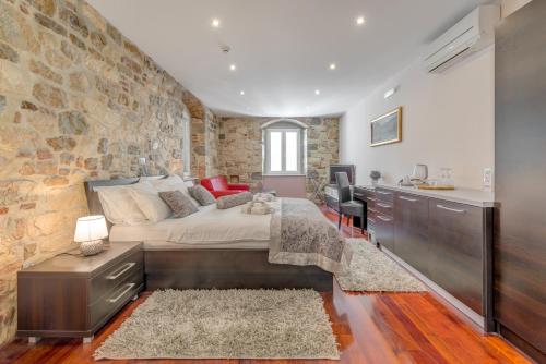 a bedroom with a large bed and a stone wall at Palace Suites Heritage Hotel - Adults Only in Split